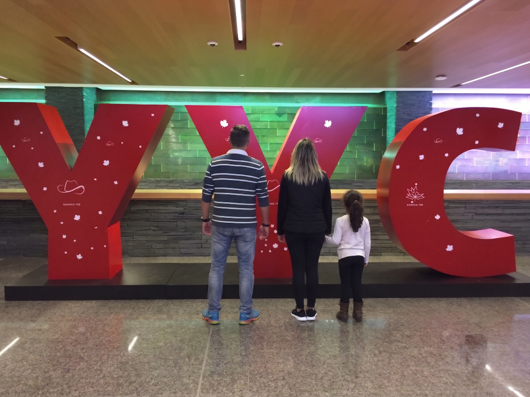 My family and me standing in front of the giant YYC letters at Calgary airport, seen from behind